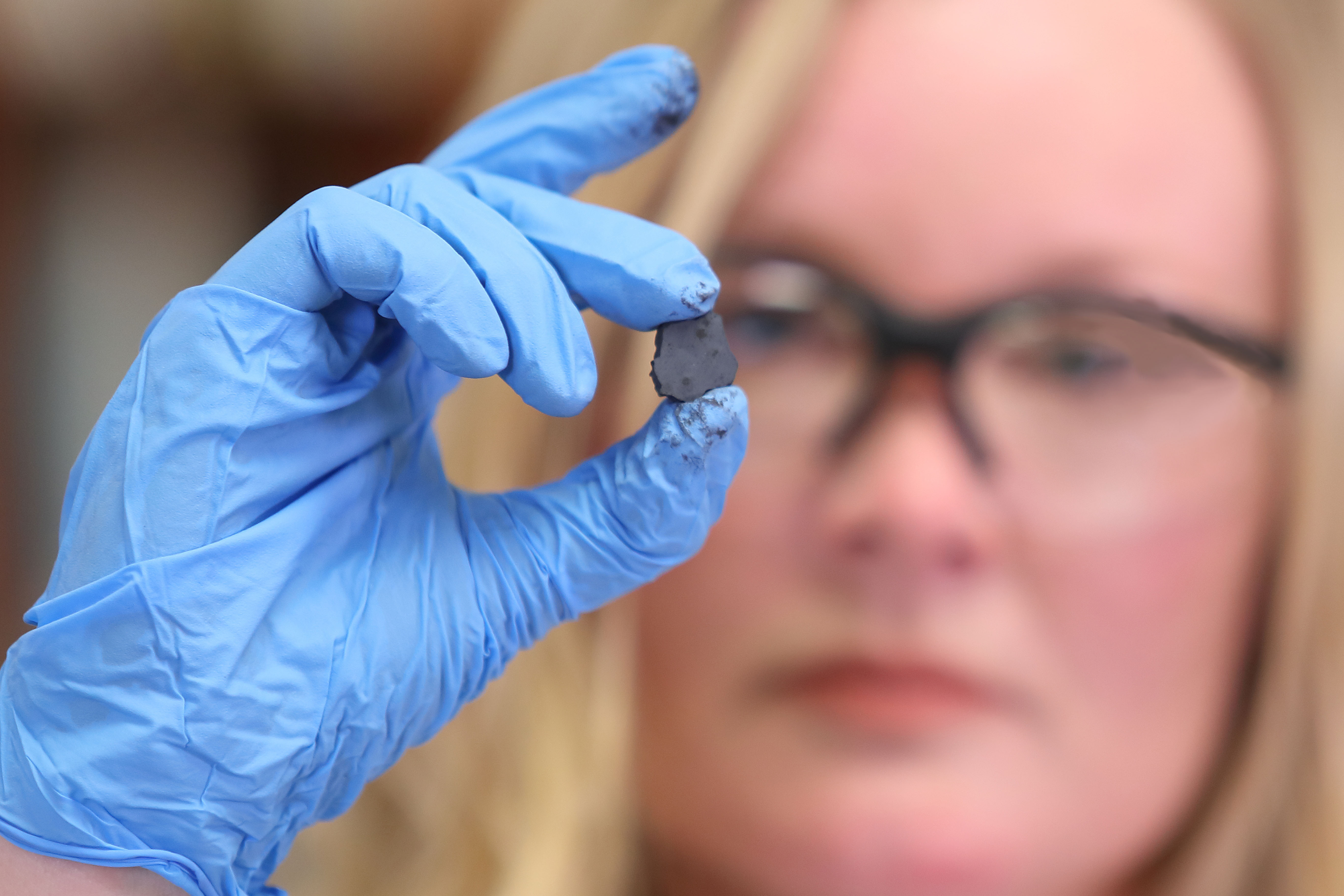 Dr. Emily Chapman wearing PPE holding up a small grey dried material which is one of the RAPC components.